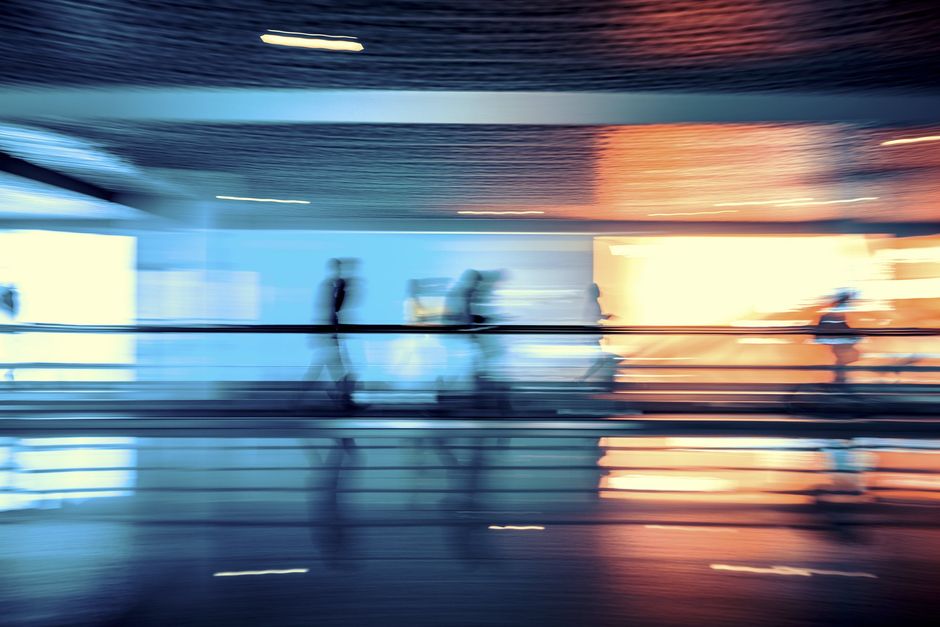 People moving through a busy transit space, motion-blurred